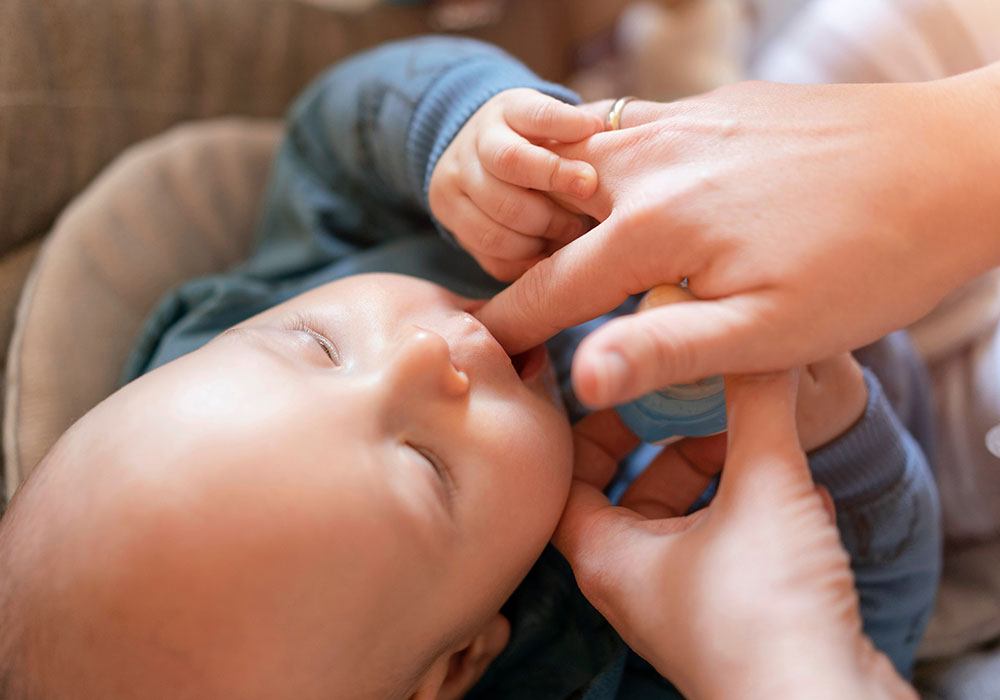 Eine Mutter massiert den Kieferkamm Ihres Babys: Massgen können gegen Zahnungsschmerz bei Babys helfen.